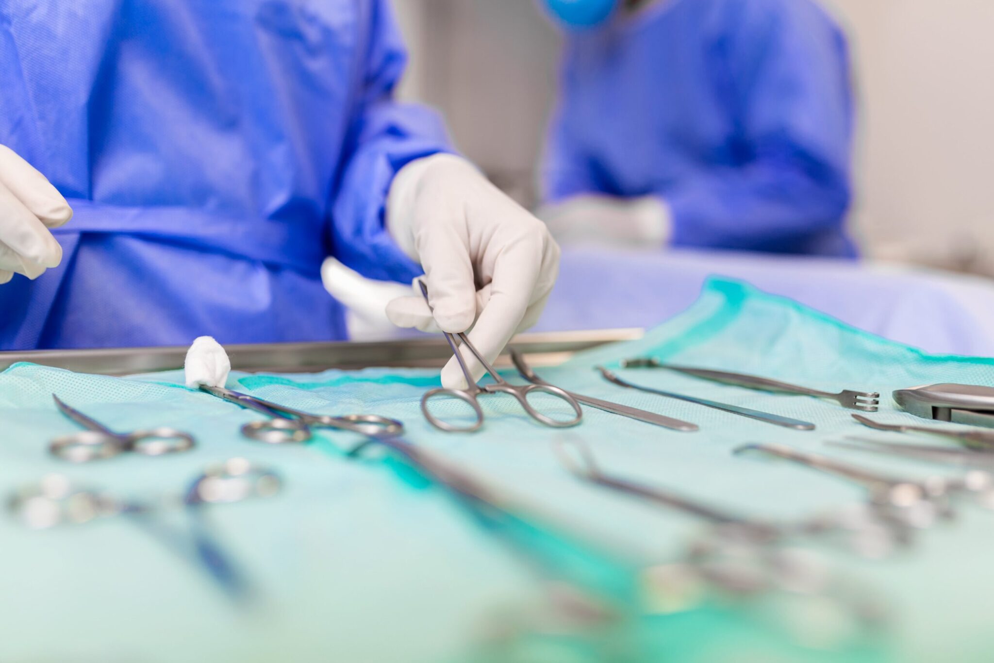 surgeon picking up surgical tool from tray surgeon is preparing surgery operating room he is hospital min scaled