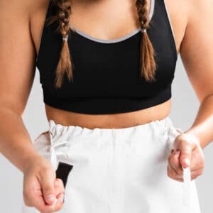 אישה מחזיקה מכנסיים מסביב למותניים