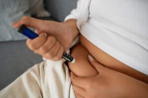 אישה מחזיקה את הבטן ומזריקה בעזרת עט